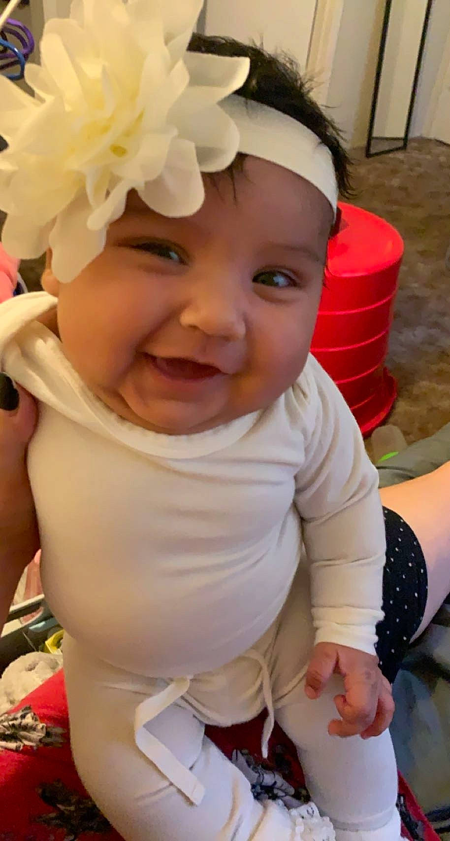 Jazmyn is registered to the contest to win money with this photo: arm, baby, baby_toddler_clothing, cheek, child, face, facial_expression, finger, hairstyle, happy, head, headgear, headwear, iris, person, pink, product, skin, sleeve, smile