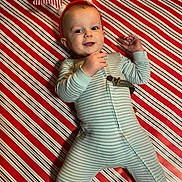 Asher joined the competition — help win amazing prizes! baby, child, pajamas, striped_clothing, reindeer_antlers, holiday, festive, smiling, lying_down, red, white, background, pattern, cute, happy, infant, indoor, person, face, celebration