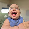 Colton joined the competition — help win amazing prizes! baby, child, smiling, happy, food, messy, face, blue_bib, high_chair, indoor, cute, laughing, infant, person, young_child, skin, expression, closeup, cheerful, fun