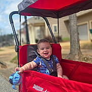 Colton joined the competition — help win amazing prizes! toddler, child, smiling, wagon, radio_flyer, red, blue, sippy_cup, outdoor, suburban, street, daytime, canopy, seatbelt, happy, person, baby, playful, sunny, toy