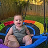 Colton joined the competition — help win amazing prizes! baby, child, swing, outdoor, grass, fence, smiling, happy, colorful, playground, summer, greenery, sunlight, cute, person, infant, play, fun, nature, leisure
