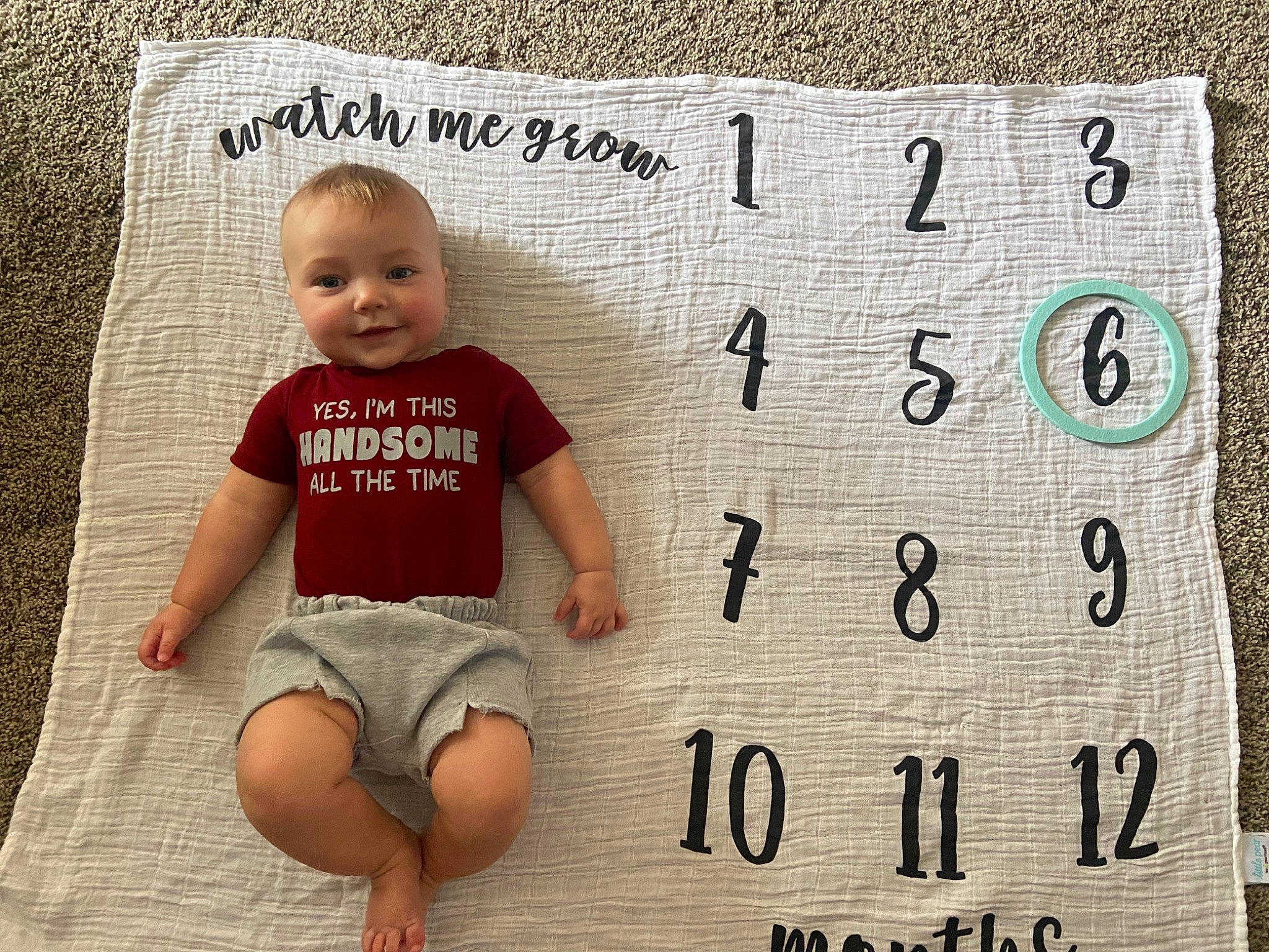 Easton is registered to the contest to win money with this photo: baby, baby_toddler_clothing, comfort, face, flooring, font, foot, happy, human_leg, joy, knee, number, pattern, person, rectangle, shorts, sleeve, smile, t_shirt, thigh