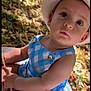 arm, baby, blanket, blue_checkered, child, curious, cute, face, hand, hat, leafy_background, nature, outdoors, person, portrait, sitting, skin, summer, sunlight, young