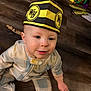 Ryder joined the competition — help win amazing prizes! baby, infant, child, paper_hat, yellow_black_hat, pajamas, onesie, wood_floor, floor, sitting, face, eyes, cheek, smile, hand, book, toy, cardboard_box, playroom, mouth