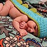 Mario joined the competition — help win amazing prizes! baby, infant, blanket, knitted_hat, dinosaur_hat, cute, resting, sleepy, soft_texture, colorful, floral_pattern, child, portrait, indoors, cozy, small_hands, expression, lying_down, warm, comfort