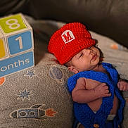 Mario joined the competition — help win amazing prizes! baby, newborn, infant, knitted_clothing, red_hat, blue_outfit, blanket, rocket_pattern, stars, blocks, months, cute, sleepy, indoors, soft_texture, child, small, resting, portrait, cozy