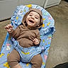 baby, child, smiling, onesie, brown_clothing, baby_chair, blue, animal_prints, happy, indoor, floor, socks, striped_socks, cute, infant, seat, clothing, person, portrait, toddler