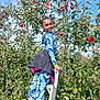apple, child, clothing, face, female, food, fruit, furniture, girl, head, nature, outdoors, pants, person, photography, plant, portrait, produce, sitting, sleeve