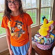Ava joined the competition — help win amazing prizes! child, glasses, orange_tshirt, mickey_mouse, witch_costume, easter_basket, plush_toy, window, indoor, table, toys, blue_shorts, carpet, green_grass, natural_light, smile, person, holiday_theme, decor, happy