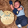 baby, newborn, sleeping, blue_clothing, mittens, plush_blanket, wooden_plaque, name_sign, infant, cute, person, resting, portrait, soft_texture, toddler, indoor, cozy, child, peaceful, lying_down