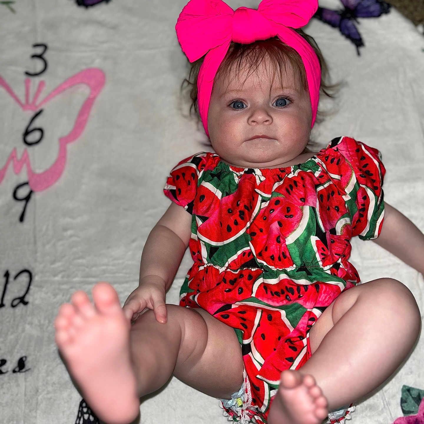 Willow is registered to the contest to win money with this photo: accessories, baby, barefoot, bodypart, clothing, cushion, dress, face, finger, formalwear, furniture, hand, head, homedecor, person, photography, portrait, purple, quilt, sitting