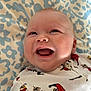 baby, smiling, onesie, clothing, pattern, incredibles, infant, face, happy, lying_down, blanket, blue, white, cute, child, portrait, infancy, human, cheerful, babywear