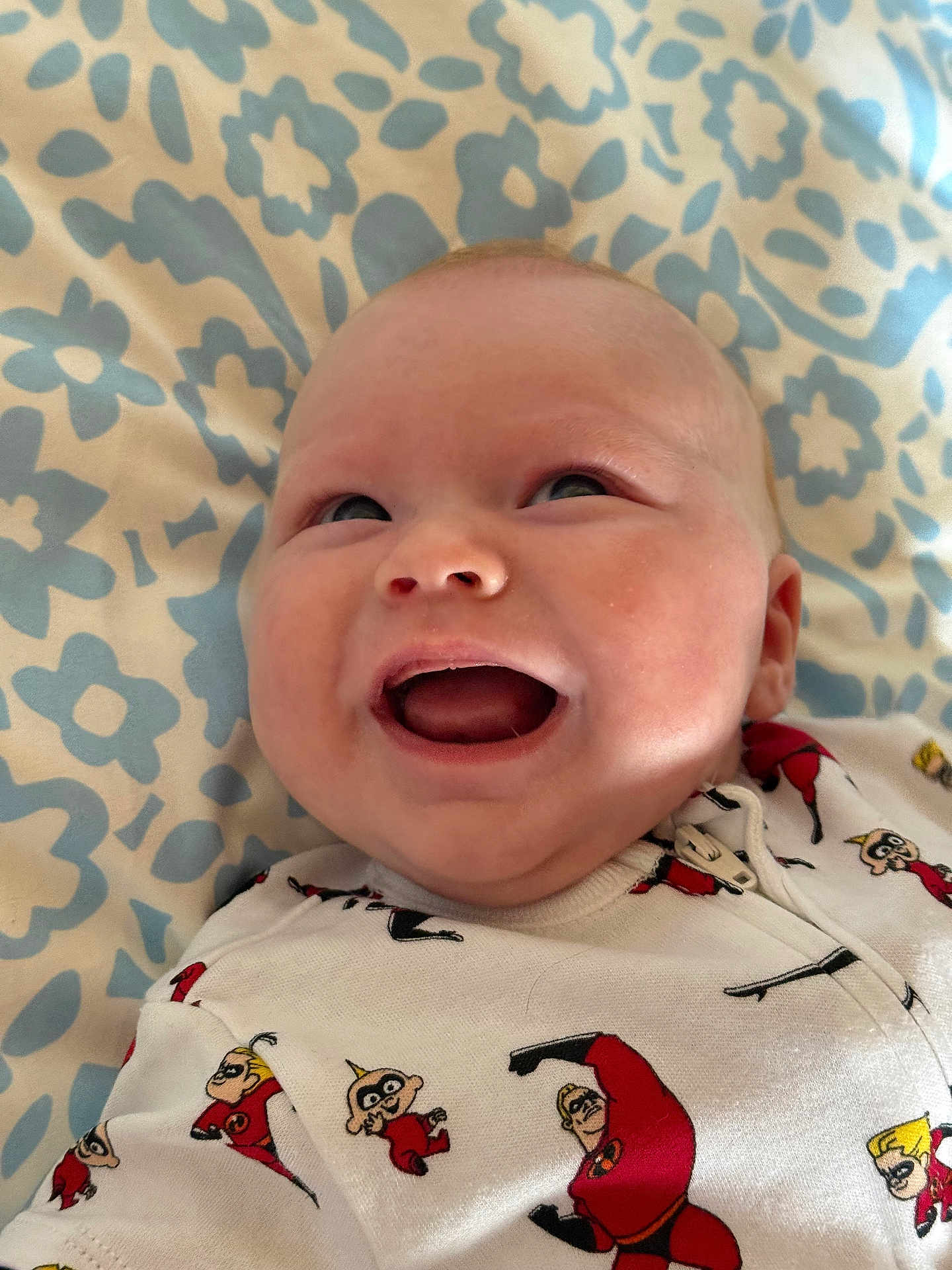 Ayden participe au concours pour gagner de l'argent avec cette photo : baby, smiling, onesie, clothing, pattern, incredibles, infant, face, happy, lying_down, blanket, blue, white, cute, child, portrait, infancy, human, cheerful, babywear
