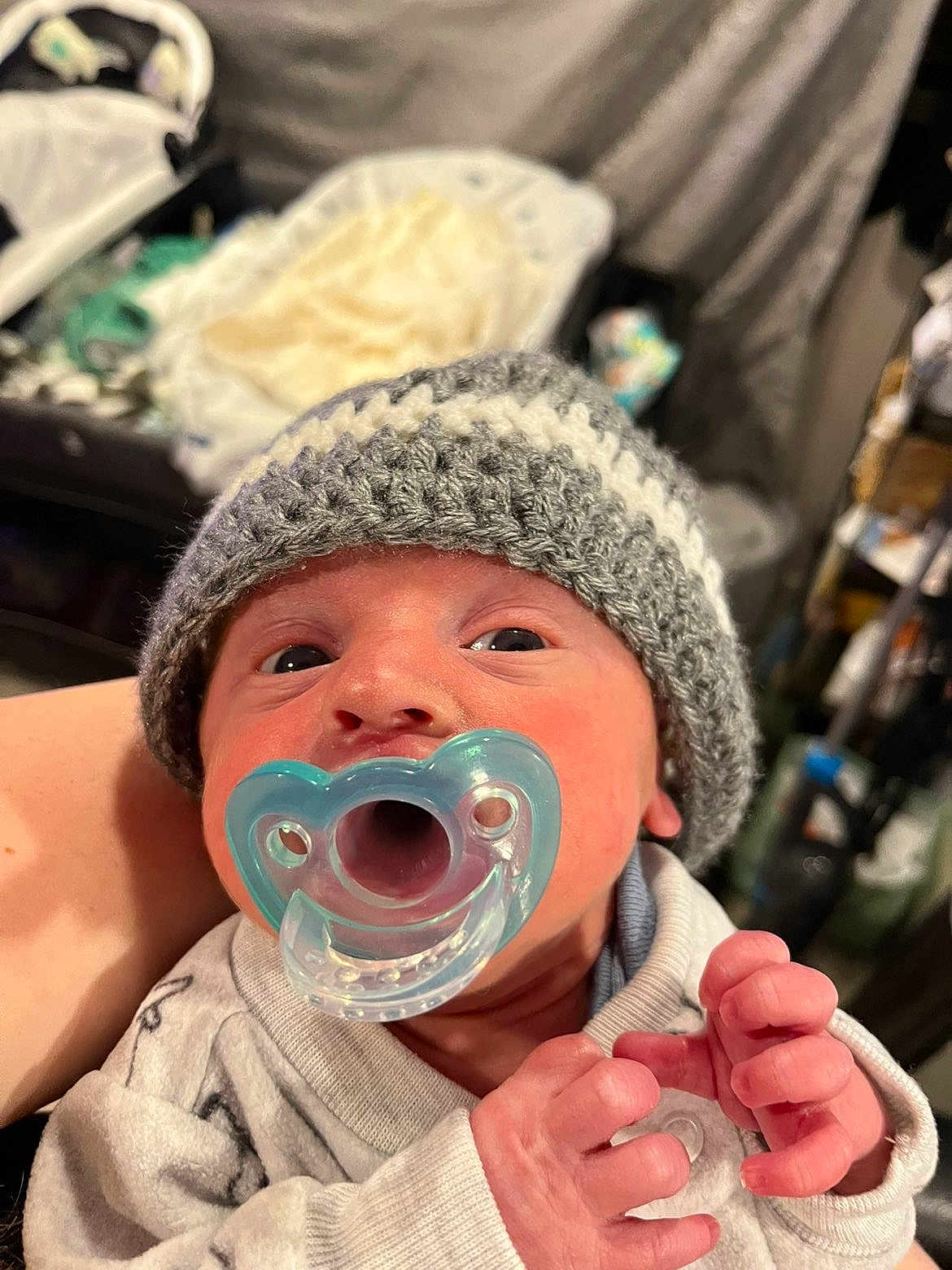 Rowan is registered to the contest to win money with this photo: baby, newborn, pacifier, knitted_hat, clothing, infant, closeup, hand, person, face, indoors, soft_light, nursery, blanket, sleepwear, cute, tiny, human, newborn_clothes, baby_hands