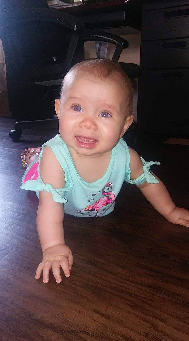 Kenzie Grace is registered to the contest to win money with this photo: baby, baby_toddler_clothing, cheek, child, crawling, finger, flash_photography, floor, flooring, fun, happy, hardwood, iris, person, sitting, skin, smile, t_shirt, thumb, toddler