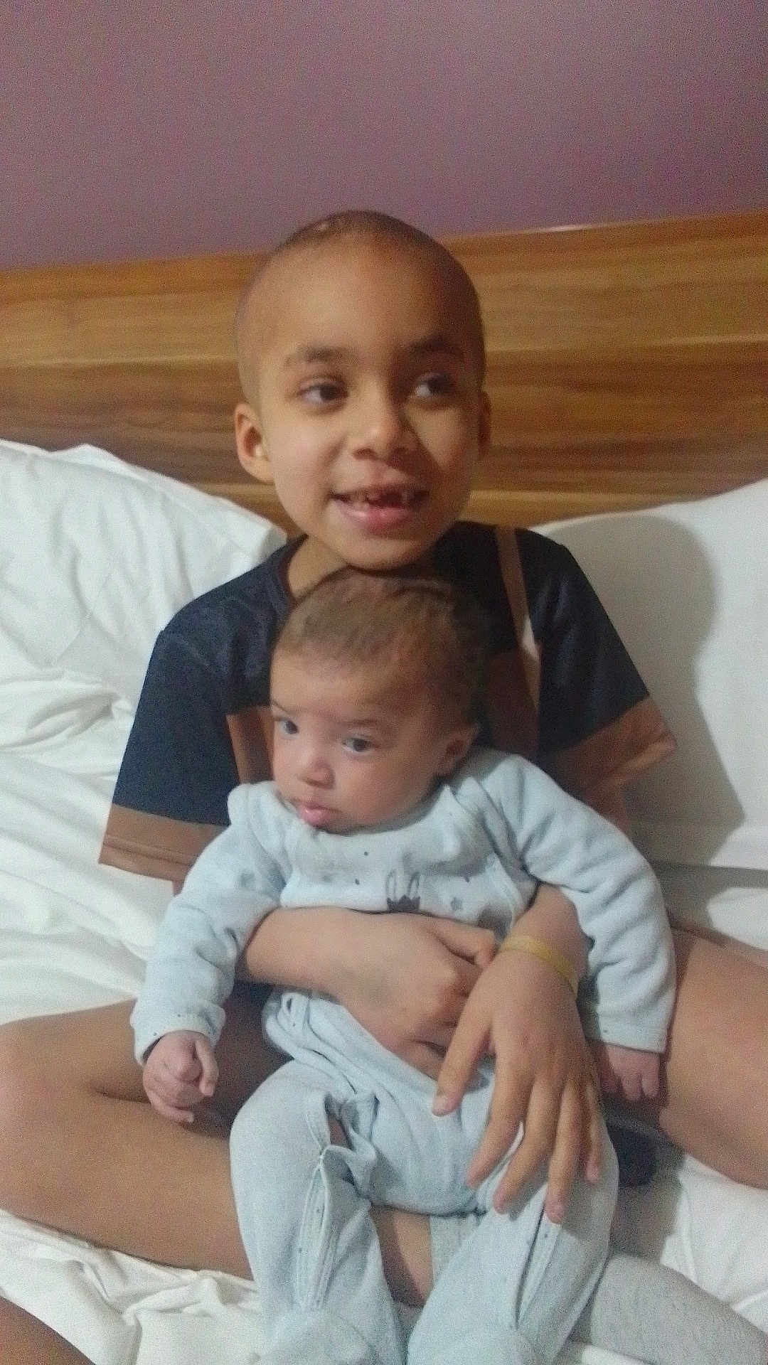 Jhalian participe au concours pour gagner de l'argent avec cette photo : child, baby, sibling, bed, pillow, blanket, headboard, onesie, pajamas, smiling, portrait, indoor, family, holding, hands, skin, eyes, hair, sitting, nursery