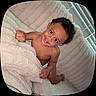 Espoir is registered to the contest to win money with this photo: toddler, child, smiling, happy, curly_hair, blanket, cozy, indoor, crawling, plush, soft_texture, face, person, baby, playful, window, blinds, skin, cute, young_child