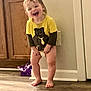 Creed is registered to the contest to win money with this photo: toddler, child, smiling, barefoot, yellow_shirt, bear_graphic, diaper, wooden_floor, kitchen, cabinet, wall, door, happy, indoors, standing, person, young_child, candid, home, cute