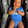 baby, black_hair, blue_outfit, car_seat, child, close_up, curly_hair, cute, happy, indoors, infant, photography, portrait, safety_harness, sitting, smiling, striped_socks, tongue_out, vehicle, white_socks