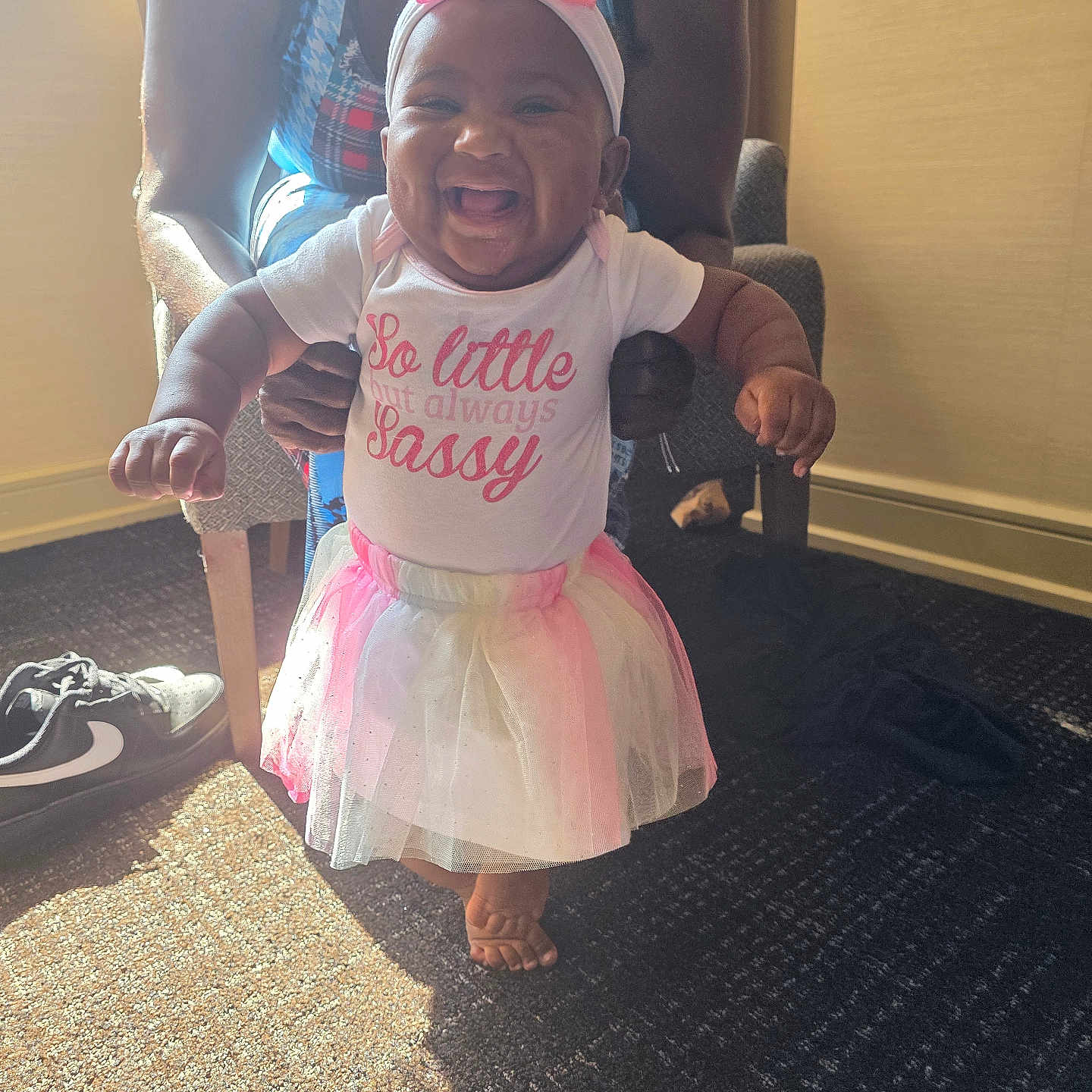 Mariah joined the competition — help win amazing prizes! adult_hands, baby, carpet, child, cute, footwear, happy, headband, indoor, infant, person, pink, shadow, shoe, smile, standing, sunlight, support, tutu, white_clothing