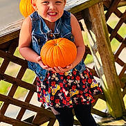 Palmer joined the competition — help win amazing prizes! child, girl, pumpkin, denim_vest, skirt, leggings, smile, outdoor, wooden_deck, fall, autumn, cheerful, holding, playful, sunlight, nature, portrait, cute, holiday, seasonal