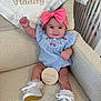 baby, child, pink_bow, blue_dress, white_shoes, frilly_socks, armchair, plaque, milestone, indoor, smiling, happy, cute, portrait, infant, furniture, blanket, crib, raised_hand, person
