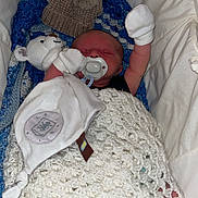 Theo is registered to the contest to win money with this photo: newborn, baby, blanket, crochet, mittens, pacifier, stuffed_animal, teddy_bear, hat, bassinet, sleeping, cozy, infant, soft_toy, foot, hand, indoors, cute, resting, child