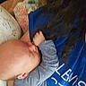 baby, infant, child, person, blue_clothing, onesie, hair, hand, face, sleeping, resting, nursing, closeup, intimate, comfort, blanket, pillow, bed, indoor, soft_lighting
