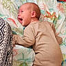 baby, infant, smiling, lying_down, bedspread, onesie, cozy, cat, animal, indoor, colorful, patterned, happy, cute, person, child, fabric, pillow, home, resting
