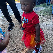 Mckenzie is registered to the contest to win money with this photo: toddler, child, red_shirt, elmo, tutu, outdoor, gravel, shoes, nike, socks, people, grass, sidewalk, casual_clothing, daylight, serious_expression, standing, toy, playing, group