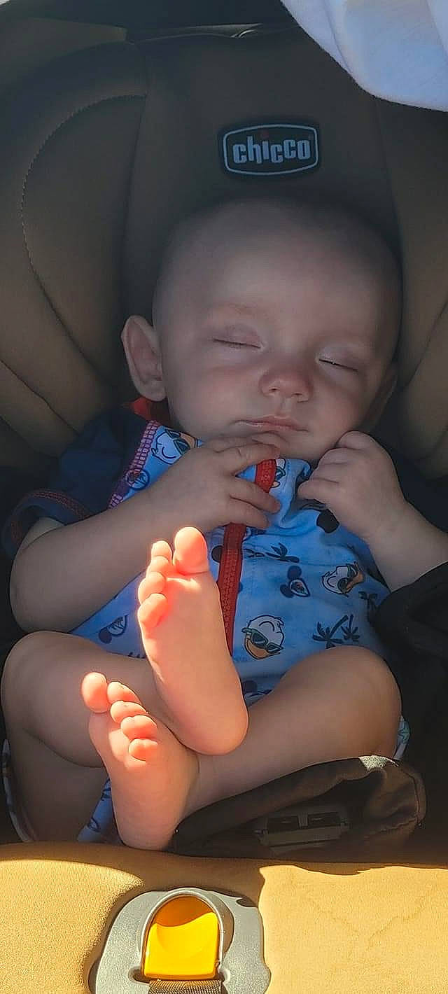 Travis is registered to the contest to win money with this photo: arm, baby, baby_toddler_clothing, cheek, chin, comfort, facial_expression, finger, gesture, hand, human_body, iris, leg, lip, mouth, neck, nose, organ, person, skin