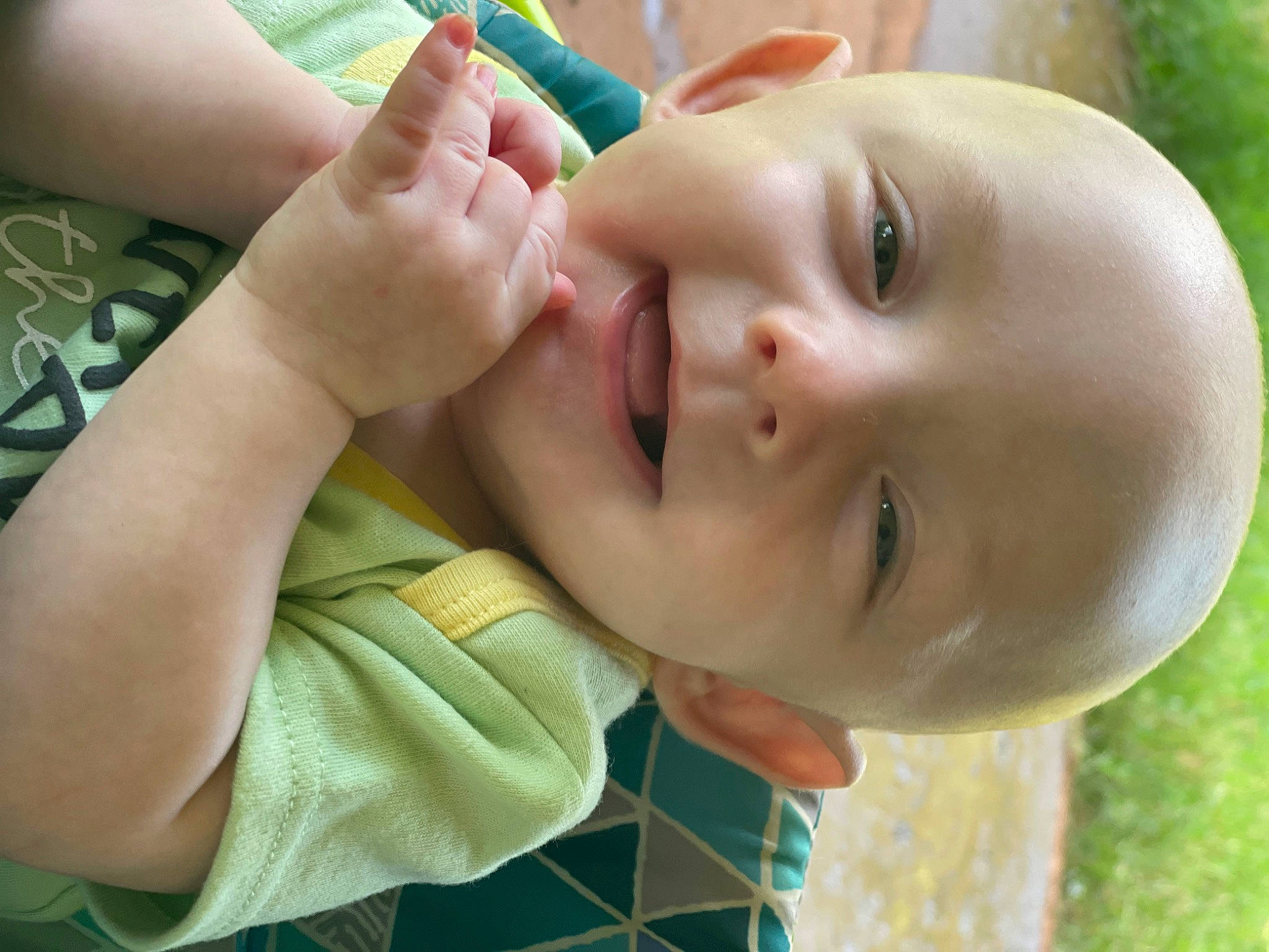 Travis is registered to the contest to win money with this photo: baby, baby_toddler_clothing, cheek, child, chin, eyebrow, eyelash, finger, gesture, grass, hand, happy, leisure, lip, mouth, neck, nose, person, skin, smile