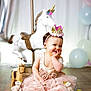 Lyana a rejoint le concours — aidez-le/la à gagner de superbes lots ! child, baby, toddler, one_year_old, crown_headband, pink_tutu, ruffled_dress, unicorn, carousel_horse, wooden_horse, stuffed_animal, balloons, alphabet_blocks, birthday_party, party_decor, smiling, sitting, wooden_floor, portrait, cute