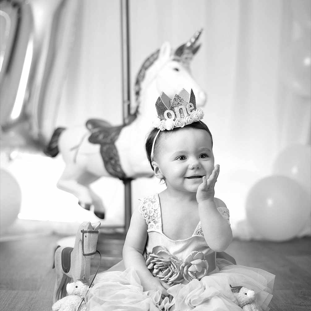 Lyana participe au concours pour gagner de l'argent avec cette photo : baby, balloons, birthday_crown, carousel, celebration, child, dress, floor, headband, party, photography, portrait, sitting, smile, stuffed_animal, toddler, toy_blocks, tutu, unicorn, wooden_horse