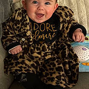 Diana a rejoint le concours — aidez-le/la à gagner de superbes lots ! baby, infant, smile, leopard_print, coat, couch, toy, portrait, happy, cute, blue_eyes, toddler, hand, clothing, indoor, plush, sitting, face, dimple, warmth