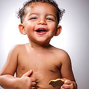 Adeen is registered to the contest to win money with this photo: toddler, child, smiling, happy, cookie, shirtless, jeans, thumbs_up, portrait, cute, baby, cute_face, short_hair, skin, hands, sitting, background, studio_light, expression, joy