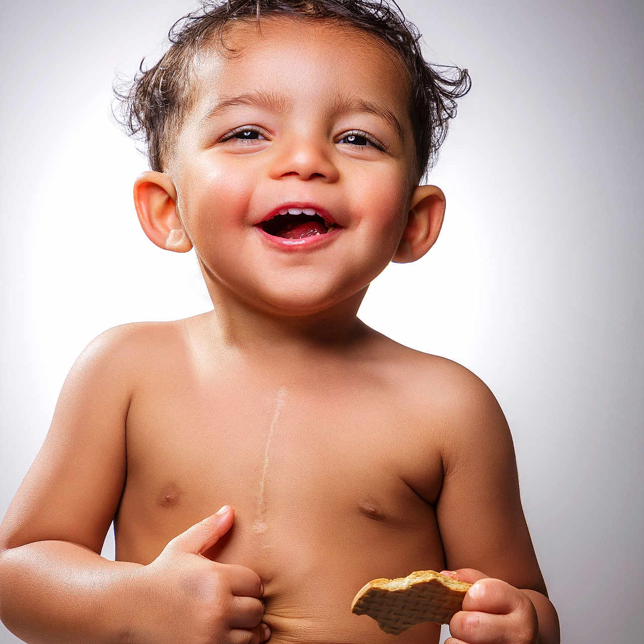 Adeen is registered to the contest to win money with this photo: baby, background, child, cookie, cute, cute_face, expression, hands, happy, jeans, joy, portrait, shirtless, short_hair, sitting, skin, smiling, studio_light, thumbs_up, toddler