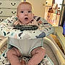 baby, infant, baby_walker, surprised_expression, indoor, furniture, dresser, legs, feet, clothing, patterned_fabric, room, door, light, floor, child, person, face, seat, toy