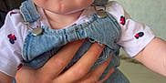 Charlotte is registered to the contest to win money with this photo: baby, child, infant, denim, overalls, hand, person, outdoor, blue_eyes, red_hair, cute, clothing, white_shirt, patterned_shirt, skin, face, legs, barefoot, holding, portrait