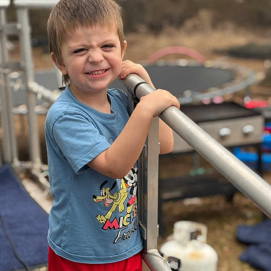 Lamar joined the competition — help win amazing prizes! child, boy, smiling, outdoor, railing, mickey_mouse, tshirt, red_shorts, playground, trampoline, grass, daylight, casual_clothing, person, young_child, happy, fun, summer, metal, background