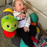 Easton is registered to the contest to win money with this photo: baby, ball, clothing, couch, cushion, face, football, furniture, glove, happy, head, homedecor, hosiery, person, photography, portrait, sitting, soccer, soccerball, sock