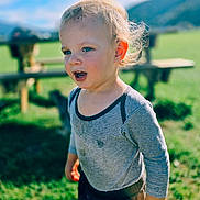 Ezio participe au concours pour gagner de l'argent avec cette photo : toddler, child, outdoor, grass, sunlight, blond_hair, striped_shirt, nature, picnic_table, blue_sky, greenery, casual_clothing, portrait, daylight, curious, young_child, expression, person, playful, background_blur