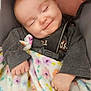 Harley is registered to the contest to win money with this photo: baby, car_seat, blanket, child, sleeping, smiling, straps, clothing, cute, infant, hands, face, comfort, soft, floral_pattern, happy, resting, cozy, portrait, indoors