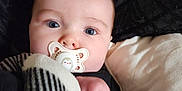 Harley is registered to the contest to win money with this photo: adorable, baby, black_background, blanket, blue_eyes, child, close_up, comfort, cute, face, indoors, infant, lying_down, pacifier, pillow, portrait, sleepy, soft_texture, striped_blanket, white_pillow