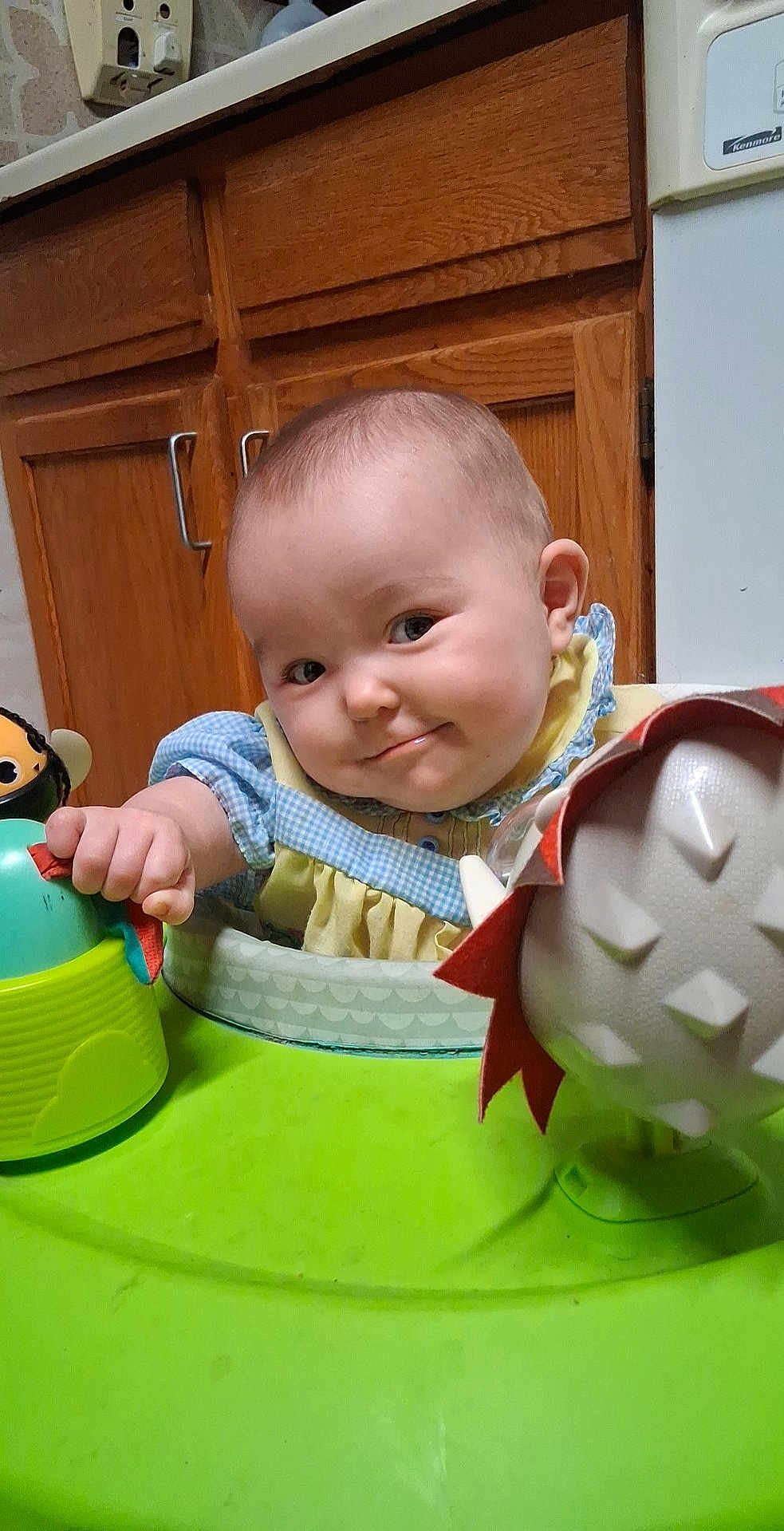 Harley joined the competition — help win amazing prizes! baby, child, infant, smile, toy, baby_walker, kitchen, cabinet, hand, face, clothing, indoor, cute, play, furniture, person, expression, yellow, blue, green