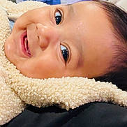 Abhimanyu is registered to the contest to win money with this photo: baby, smiling, face, closeup, cozy, fleece, child, infant, happy, portrait, indoors, soft_texture, bright_eyes, cute, lying_down, warm_clothing, background_blur, toy, colorful, skin