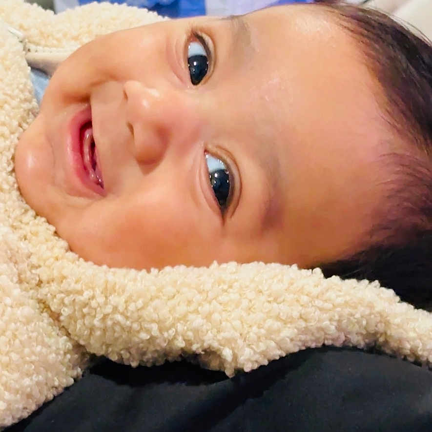 Abhimanyu is registered to the contest to win money with this photo: baby, smiling, face, closeup, cozy, fleece, child, infant, happy, portrait, indoors, soft_texture, bright_eyes, cute, lying_down, warm_clothing, background_blur, toy, colorful, skin