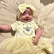 Dakota joined the competition — help win amazing prizes! baby, bed, blanket, bow, child, clothing, cute, happy, headband, human, indoors, infant, lying_down, person, portrait, smiling, soft_lighting, toddler, tulle_skirt, yellow_dress