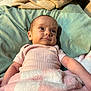 Dakota is registered to the contest to win money with this photo: baby, infant, blanket, bed, pillow, pink_shirt, ribbed_clothing, lying_down, face, head, skin, expression, indoor, cozy, soft_texture, child, person, sleepwear, cute, young