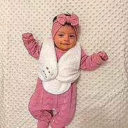 éline a rejoint le concours — aidez-le/la à gagner de superbes lots ! baby, blanket, bow, child, cozy, cute, footed_pajamas, happy, headband, indoor, infant, lying_down, newborn, pink_clothing, portrait, raised_arms, sleepwear, smiling, soft, textured_blanket